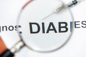 Fototapeta premium Words diabetes diagnosis with syringe through magnifying glass.
