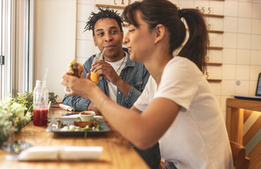 Young couple sitting in street fast food restaurant,eating burgers and drinks fresh organic juice.	
