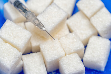 Heap of sugar and syringe on blue background. Testing, treatment diabetes concept