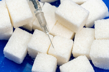 Heap of sugar and syringe on blue background. Testing, treatment diabetes concept
