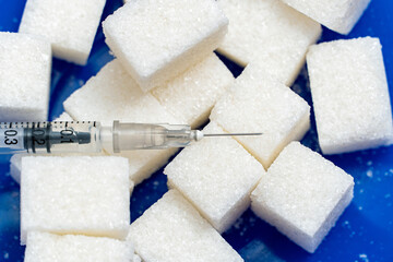Heap of sugar and syringe on blue background. Testing, treatment diabetes concept