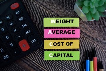 WACC - Weight Average Cost of Capital write on sticky notes isolated on Wooden Table.