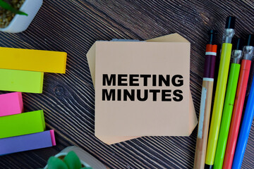 Meeting Minutes write on sticky notes isolated on Wooden Table.