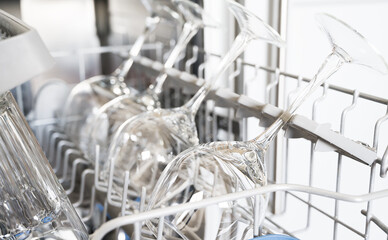 Row od perfectly clean wine glasses in dishwasher. House chores concept.