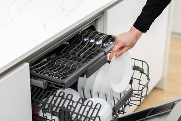 Housewife taking clean dishes out of dishwashing machine