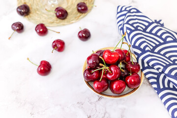 bowl of cherries on marble background and wicker tablecloth