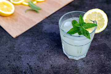 glass of lemonade with lemon wedge and peppermint - mojito