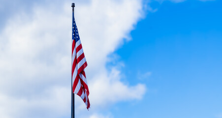 United States of America flag at rest. Blue sky puffy clouds. Room for copy text. 