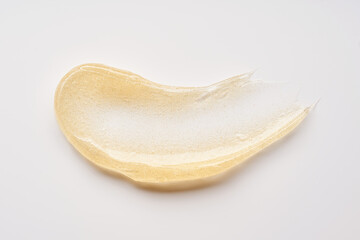 Transparent smear and texture of golden cosmetic gel on a white background.