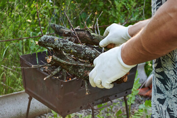 A guy in white mittens prepares a fire for a grill