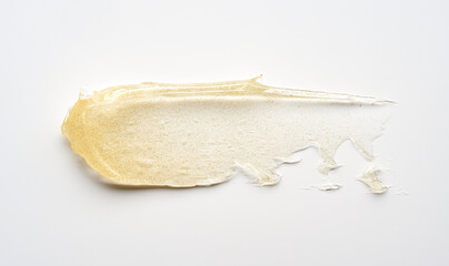 Transparent smear and texture of golden cosmetic gel on a white background.