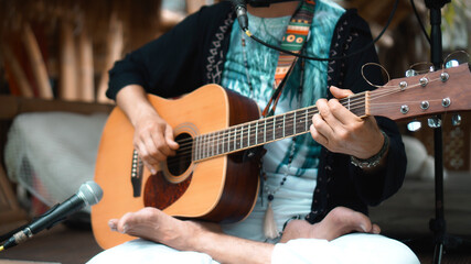 Obraz premium The young man plays hands and on a classic acoustic wooden guitar on the street