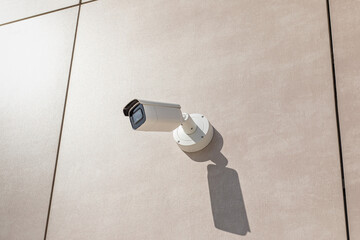 Cctv camera on wall of building in city. Security tracking concept close-up with flare.
