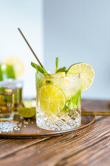 Bright photography of a cold drink, a glass of mojito with mint leaf, ice, lemon and sugar on a...