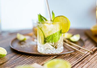 Bright photography of a cold drink, a glass of mojito with mint leaf, ice, lemon and sugar on a wooden table with retro style