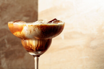 Iced coffee with natural ice and cream on a brown background.