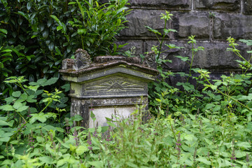 schöner alter Grabstein  hinter Unkraut auf einem Wuppertaler Friedhof