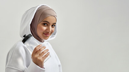 Portrait of smiling young arabic girl holding sport bottle