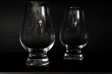 Two empty whisky tulip glasses on dark background