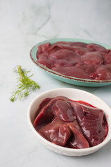 raw chicken liver with herbs in a green plate, green background
