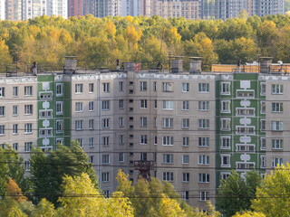 Soviet architecture panel multi-storey residential building fasad at summer days among the trees