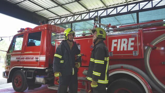 A successful group of caucasian firefighters or firemen team with uniform high five, working on their career. An emergency accident rescue. People. Hero teamwork with a fire truck car. Service job