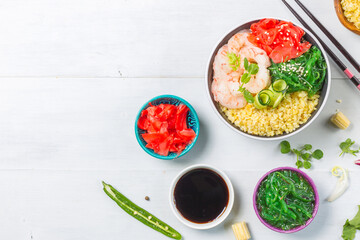 Poke, one of the main dishes of Hawaiian cuisine. Bowl with bulgur, shrimp, chuka salad. On a gray wooden background with cooking ingredients and teriyaki sauce . Horizontal, overhead