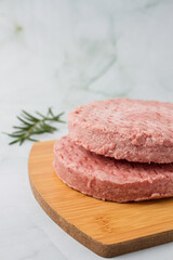raw burger meat with herbs over a wood table, green background