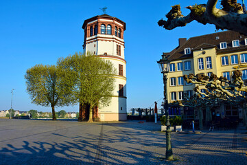 Naklejka premium City embankment with an old tower in the sun