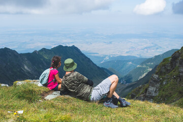 Father with his little girl resting on a mountain top and admiring the landscape