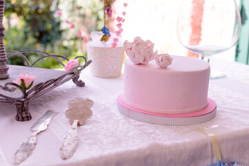 Mesa de cumpleaños con torta, cubiertos y adornos en tonos rosa pastel