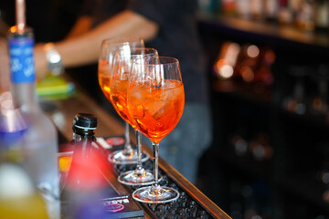 three glasses of cocktails on the bar. bartender pours a glass of sparkling wine with Aperol. - 440840445