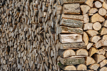 Background of hewed smooth wooden logs. Cut wood texture. Pile of chopped fire wood prepared for...