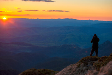 Fototapeta premium Man in top of mountain photographing the beautiful landscape at sunrise