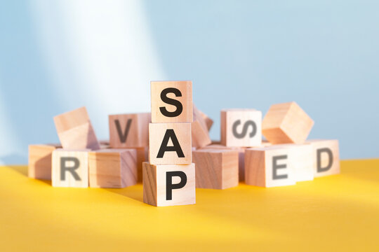 wooden cubes with letters sap arranged in a vertical pyramid, yellow background, reflection from the surface of the table, business concept