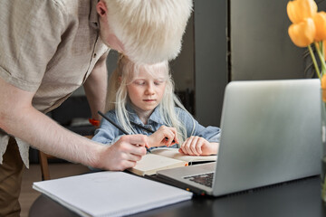 Girl stuck with hard task and preparing homework with caring her bearded father