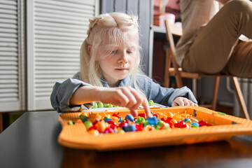 Girl reaching for the detail of her game while folding it
