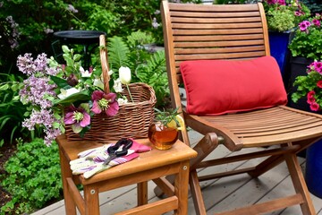 Backyard garden oasis with beautiful bouquet of seasonal cut flowers and glass of ice tea beverage for relaxing and enjoying secluded quiet time on warm summer afternoon staycations