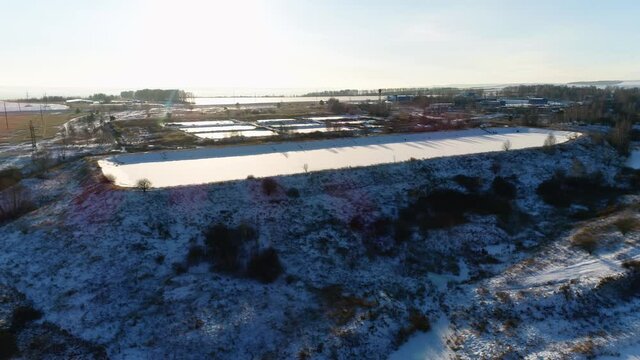 Huge reservoir on snowy hill at wastewater treatment plant under clear sky at sunset in winter evening bird eye view