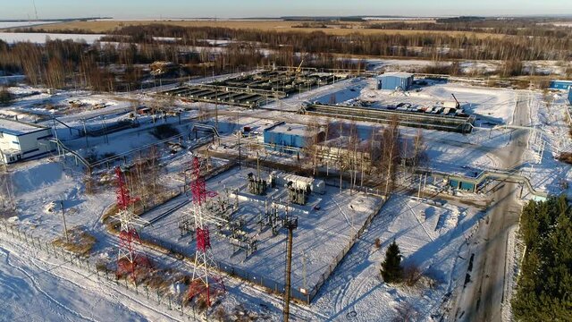 Electricity production substation at wastewater treatment plant against bare forest in winter evening bird eye view