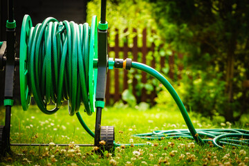 Garden hose for watering plants in garden - obrazy, fototapety, plakaty