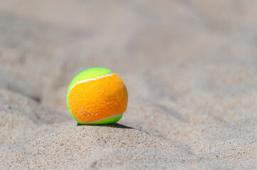 Fototapeta na wymiar Tennis ball on the sand at the beach close up