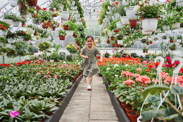Caucasian girl running through the greenhouse while spending time around the flowers