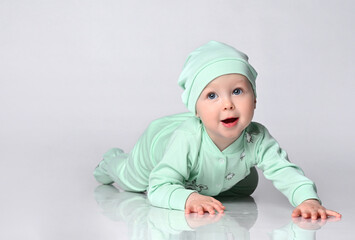 joyful baby infant A toddler in a cotton jumpsuit and a matching cap learns to crawl.