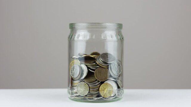 Decrease of coins in the glass jar - stop motion footage. Saving money concept.