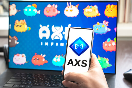 Russia Moscow 30.05.2021.Logo,screenshot of blockchain nft ethereum cryptocurrency game Axie in laptop,mobile phone.Man playing,collecting,creating crypto pet,heroes. Earning digital money tokens AXS