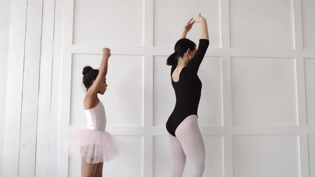 Woman teaching African girl how to dance ballet
