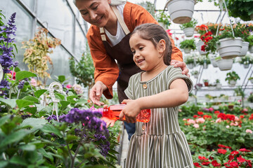 Girl holding plastic bottle and spraying with water at the flowers