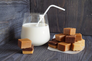 A delicious snack — a glass of milk with a straw and a pyramid of toffee next to it