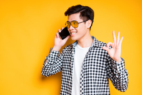 Happy Asian Guy In Shirt Talking On The Phone Wearing Sunglasses And Showing Okay Sign With His Hand